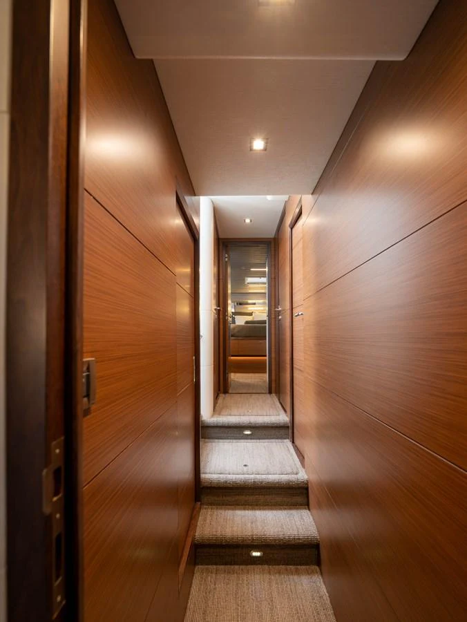 A sleek hallway with wooden paneling and carpeted steps leading to another area of the yacht. aboard SUB-PAR Yacht for Sale