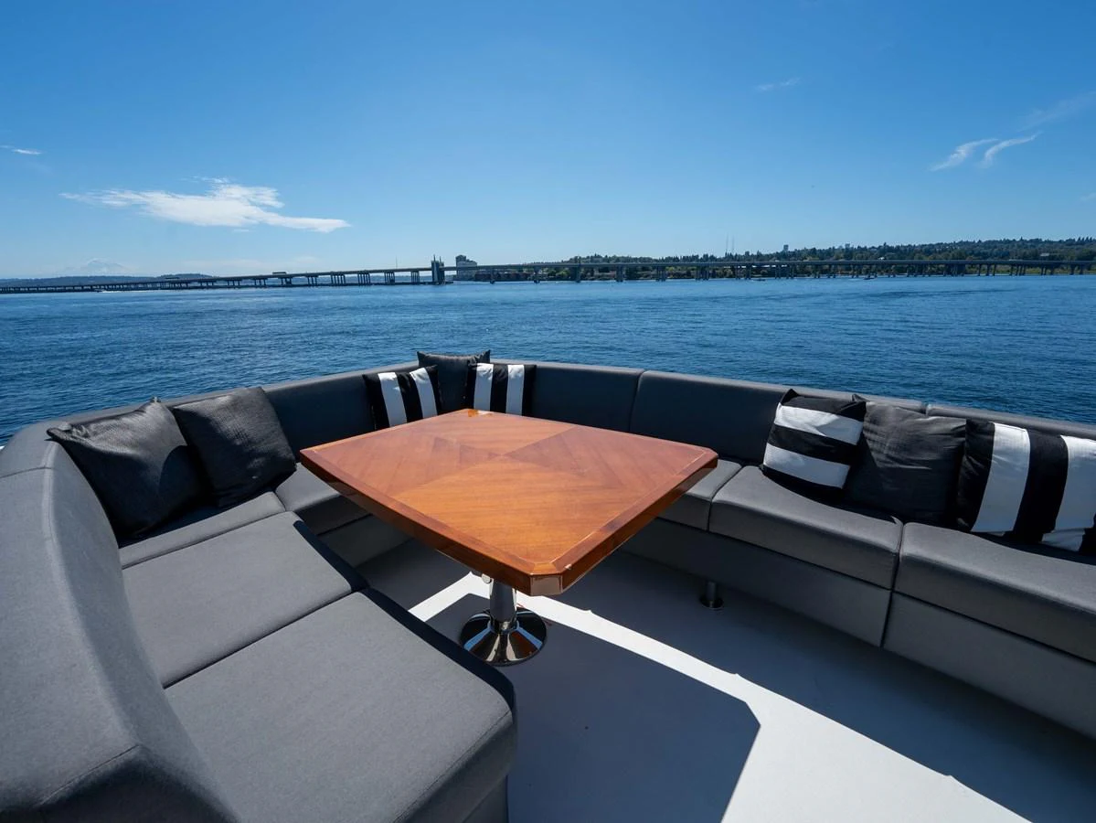 The aft deck features a spacious seating area with a stylish wooden table, perfect for outdoor relaxation and dining. aboard SUB-PAR Yacht for Sale