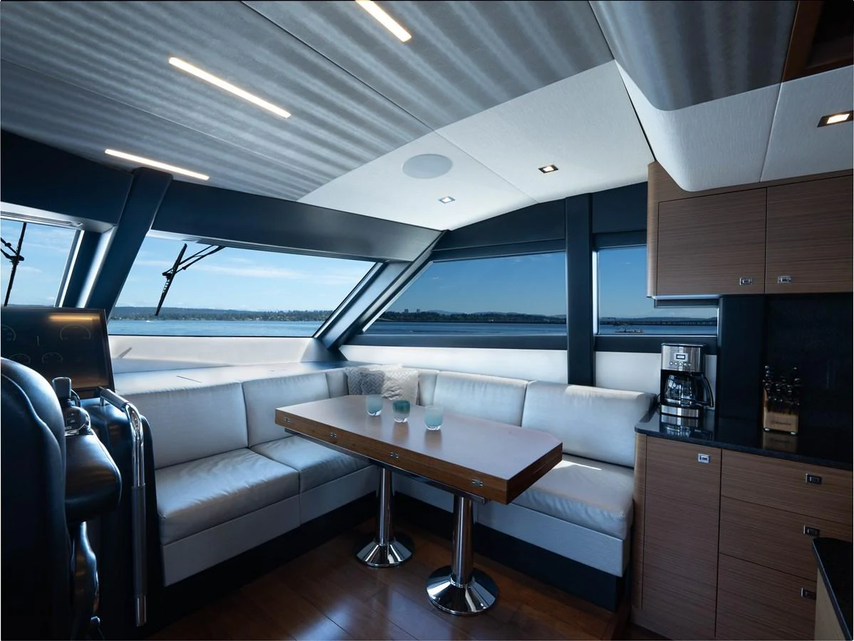 The yacht's salon features a comfortable seating area with a wooden table and panoramic windows offering stunning views. aboard SUB-PAR Yacht for Sale