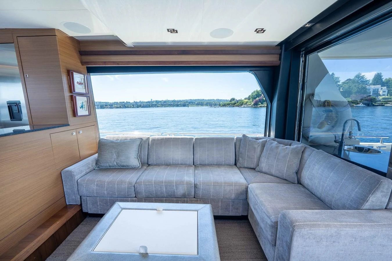 The salon features a comfortable L-shaped sofa with a stunning view of the water through large windows. aboard SUB-PAR Yacht for Sale