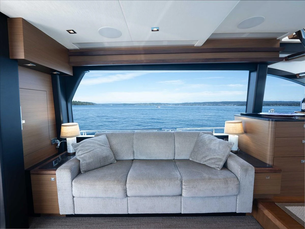 The salon features a comfortable sofa with a stunning view of the water through large windows. aboard SUB-PAR Yacht for Sale