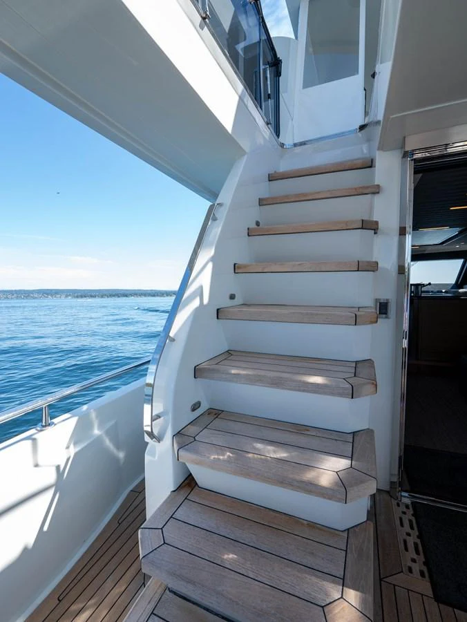 A sleek staircase with wooden steps leads to the upper deck, offering a seamless transition between levels. aboard SUB-PAR Yacht for Sale