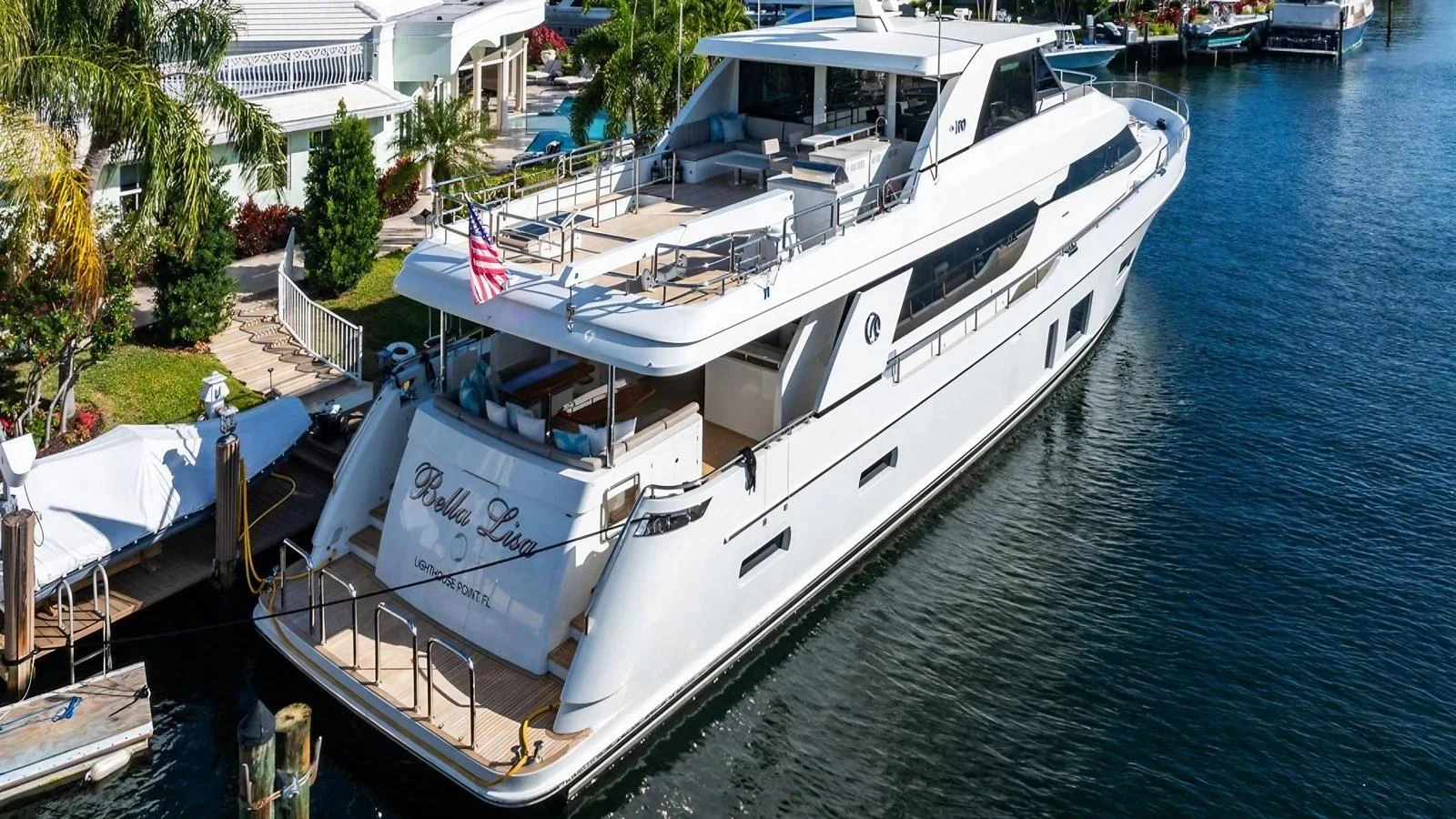 A sleek and modern yacht is docked at a marina, showcasing its spacious aft deck and elegant design. aboard BELLA LISA Yacht for Sale