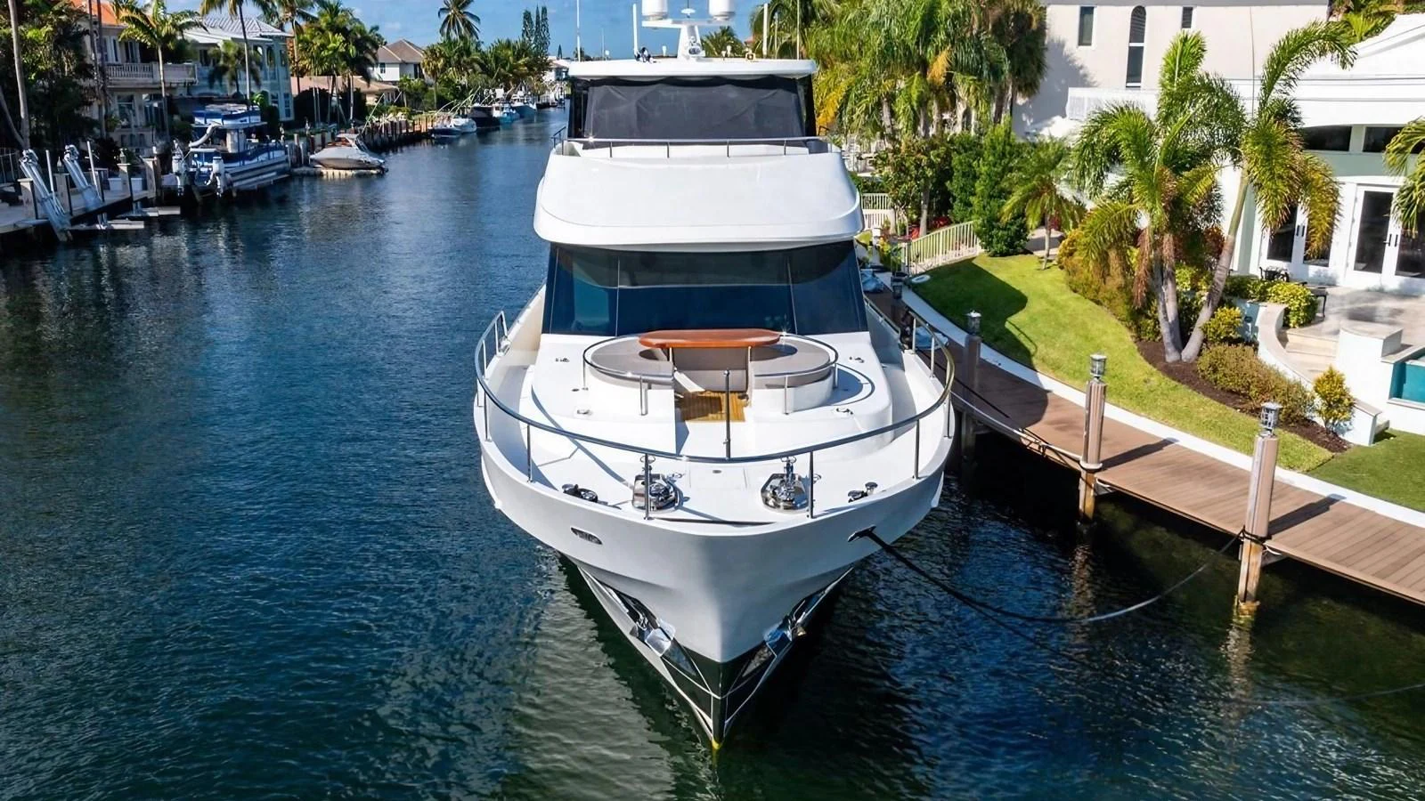 A luxurious yacht is docked in a serene canal, showcasing its sleek design and inviting bow seating area. aboard BELLA LISA Yacht for Sale