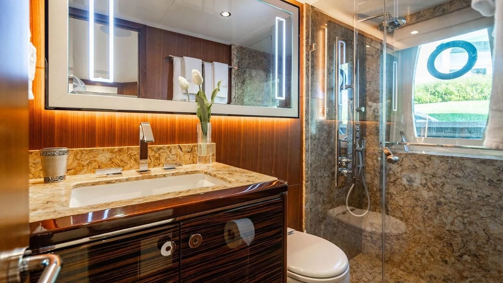 The bathroom features elegant wood paneling, a marble countertop, and a spacious shower area. aboard BELLA LISA Yacht for Sale