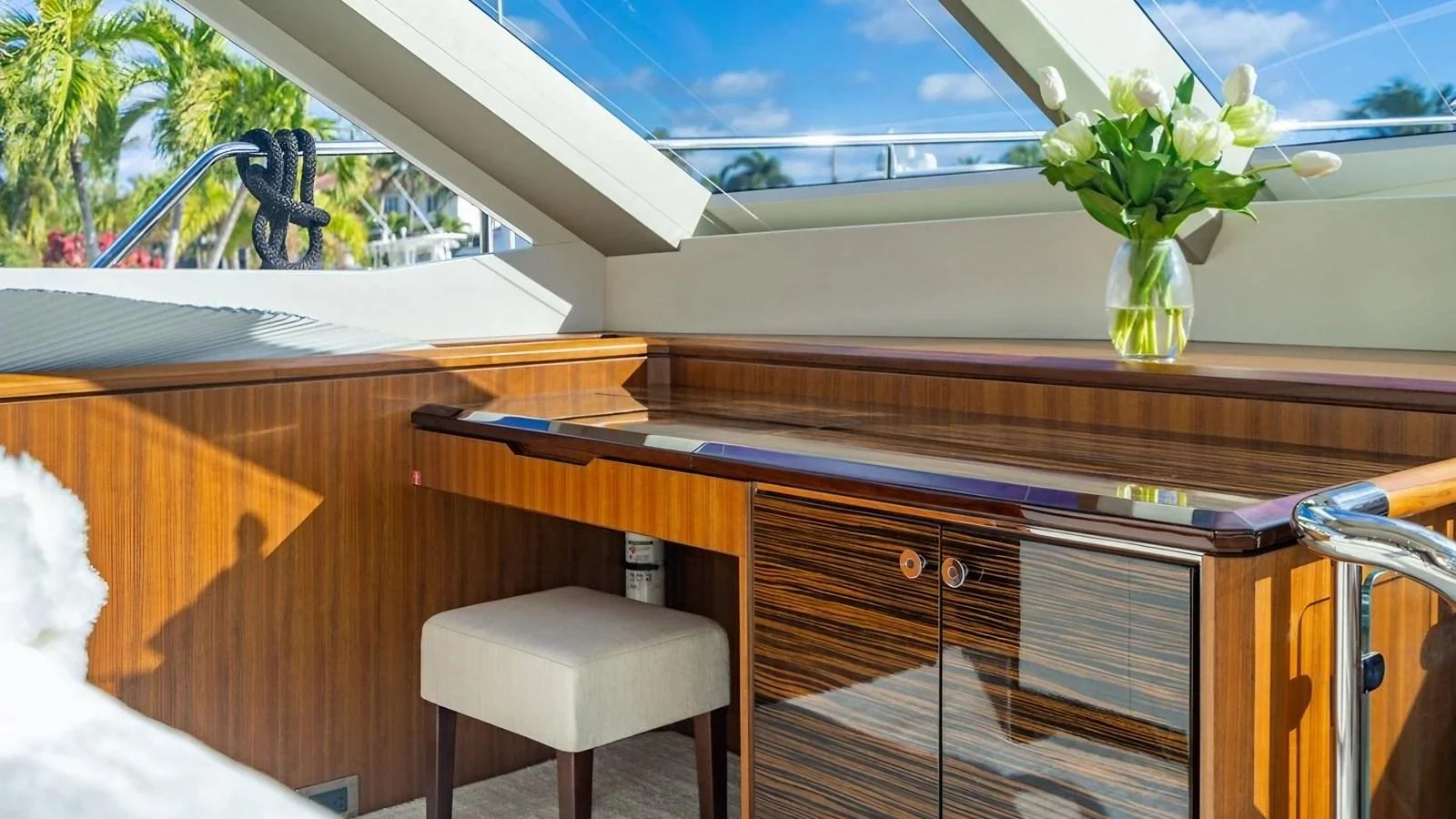 A well-lit desk area with a wooden finish and a vase of flowers under a skylight. aboard BELLA LISA Yacht for Sale