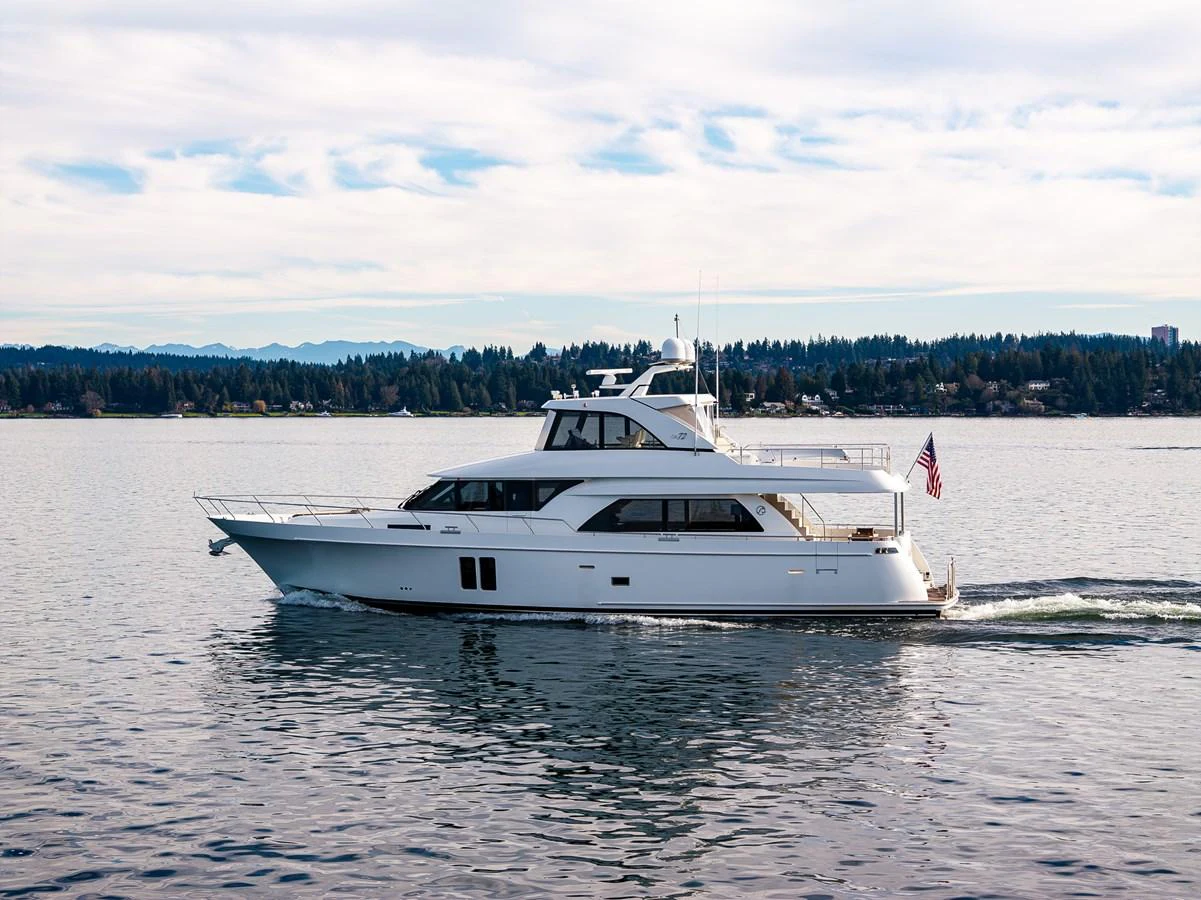 A sleek white yacht cruises gracefully on calm waters with a scenic shoreline in the background. aboard ISLAND BREEZE Yacht for Sale