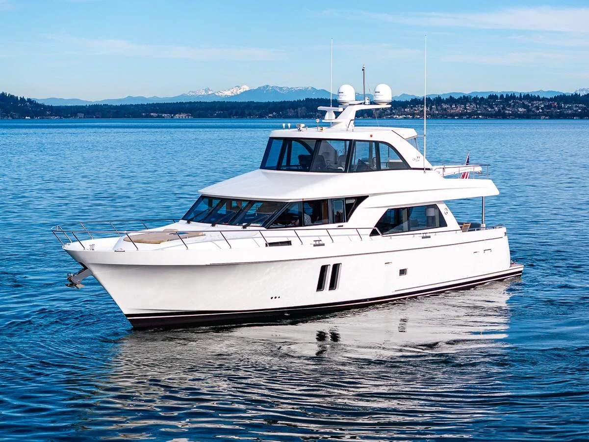 A sleek white yacht cruises on calm waters with a scenic backdrop. aboard ISLAND BREEZE Yacht for Sale