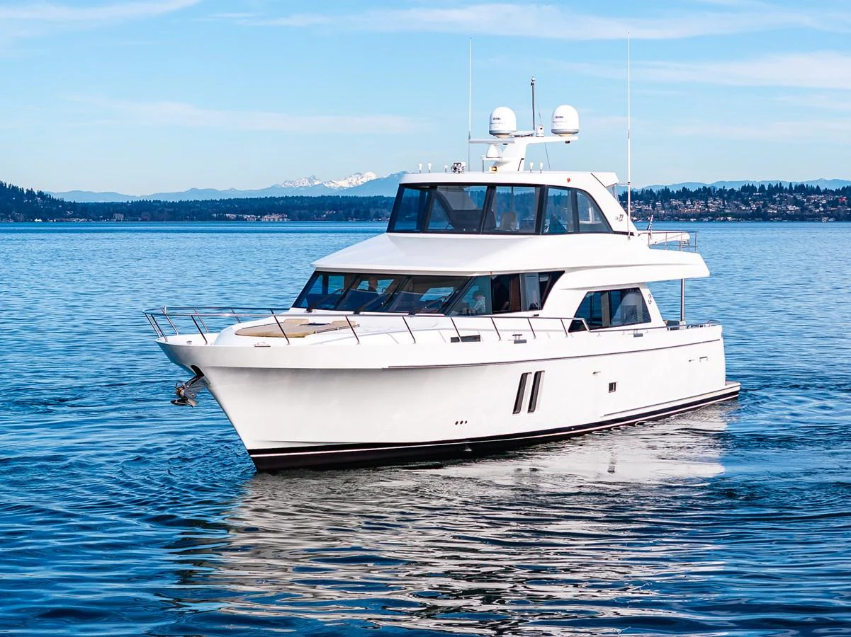A sleek white yacht cruises gracefully on calm waters under a clear blue sky. aboard ISLAND BREEZE Yacht for Sale