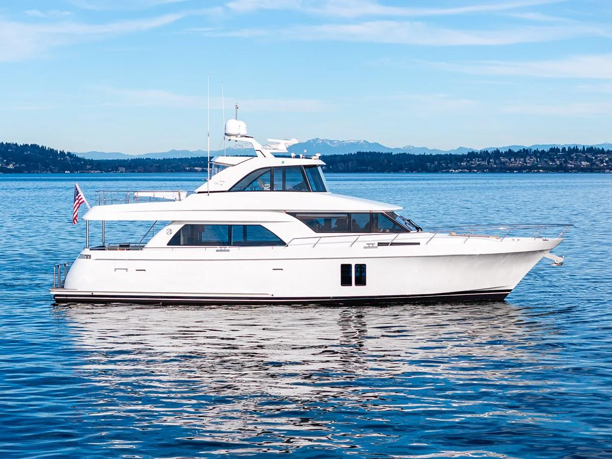 A sleek white yacht glides gracefully on calm waters under a clear blue sky. aboard ISLAND BREEZE Yacht for Sale