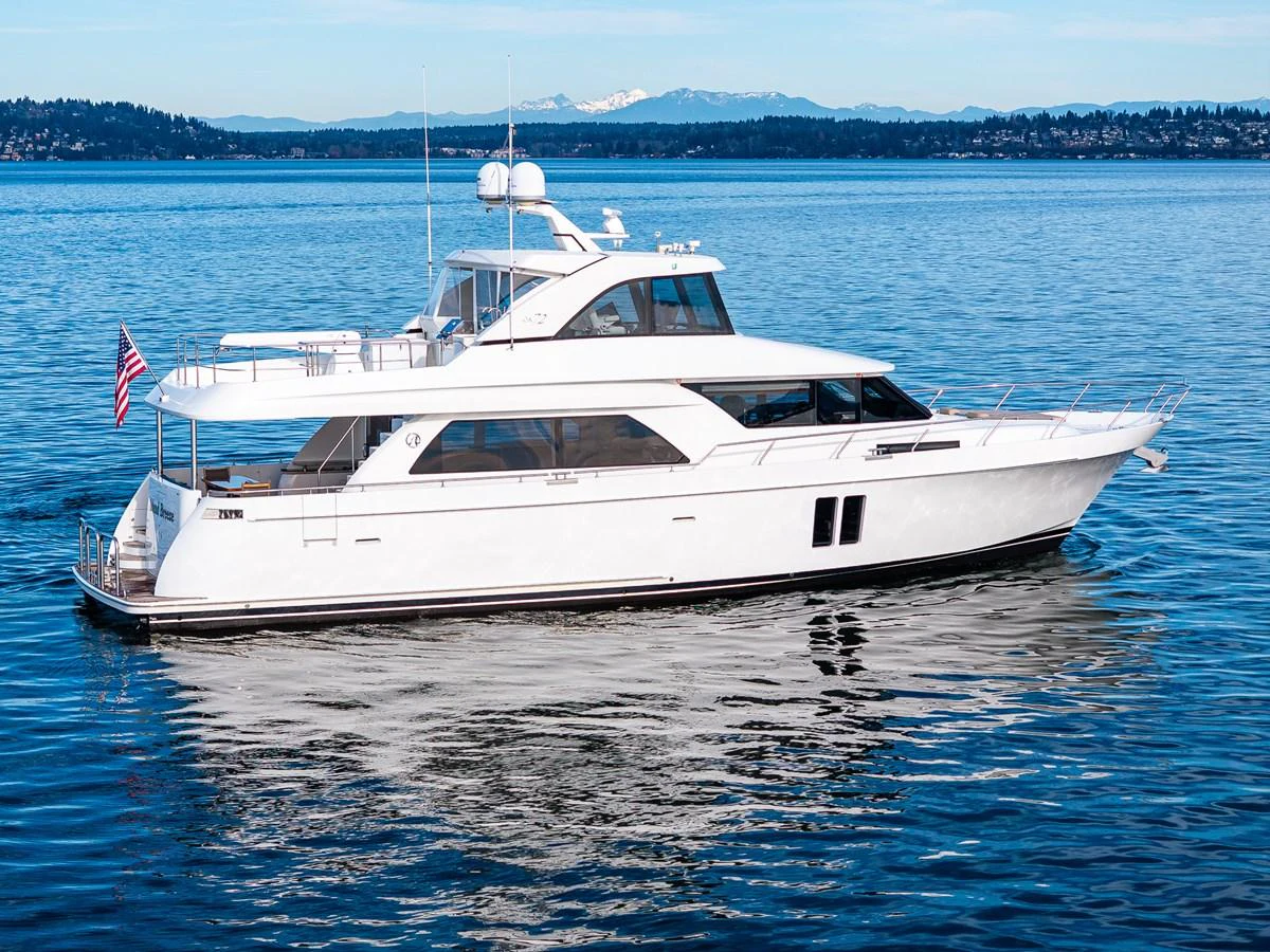 A sleek white yacht glides gracefully on calm waters with a scenic backdrop. aboard ISLAND BREEZE Yacht for Sale