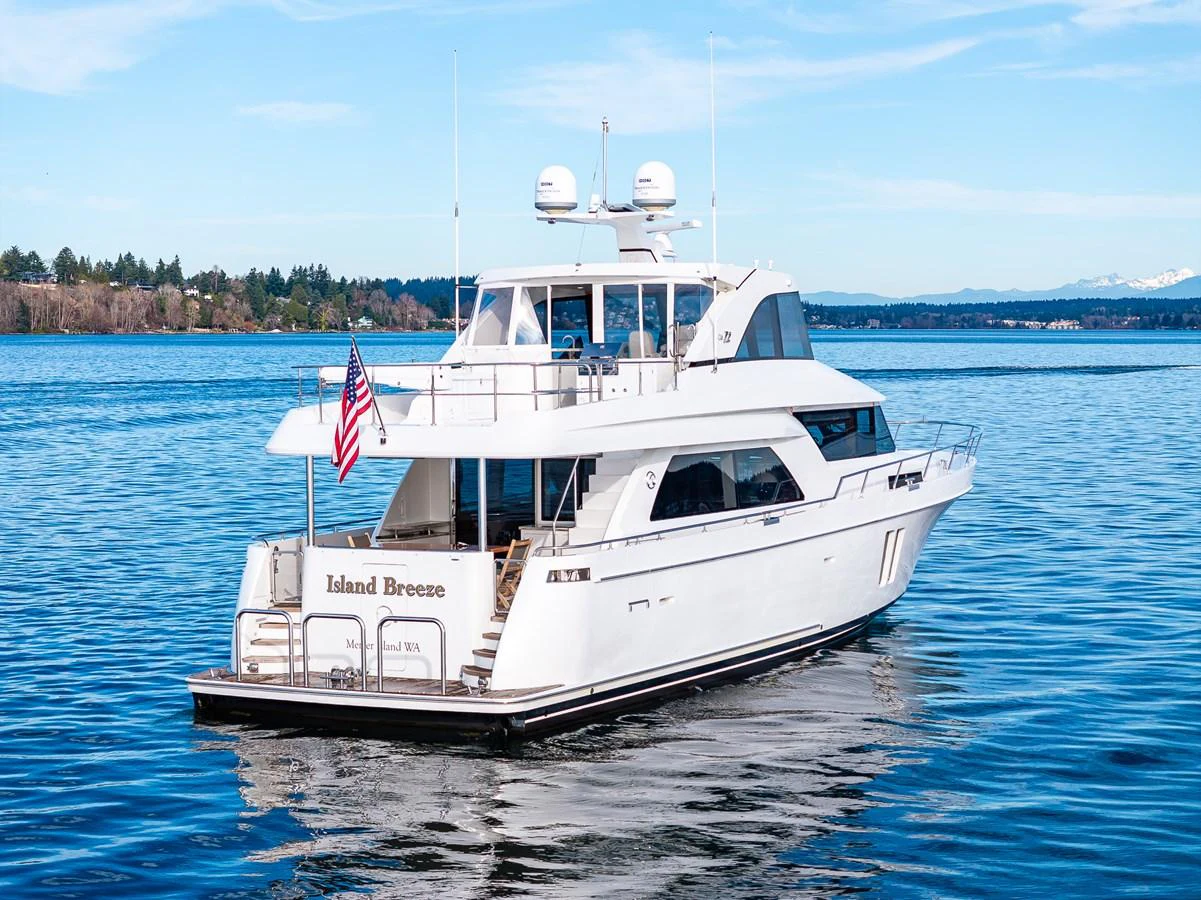 A pristine yacht named 'Island Breeze' is anchored on calm waters with a scenic backdrop. aboard ISLAND BREEZE Yacht for Sale