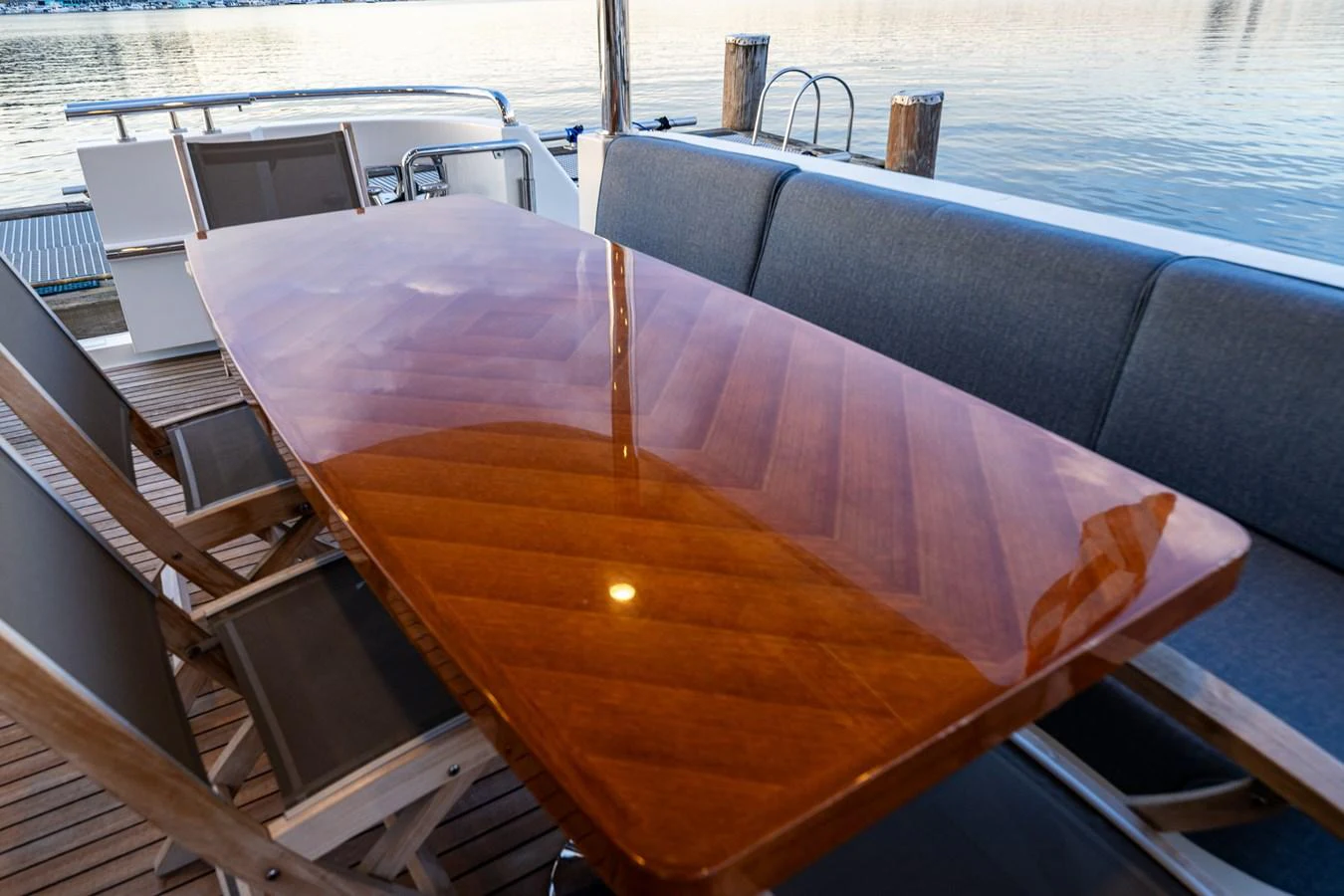 The aft deck features a polished wooden dining table with comfortable seating, perfect for enjoying meals with a view of the water. aboard ISLAND BREEZE Yacht for Sale