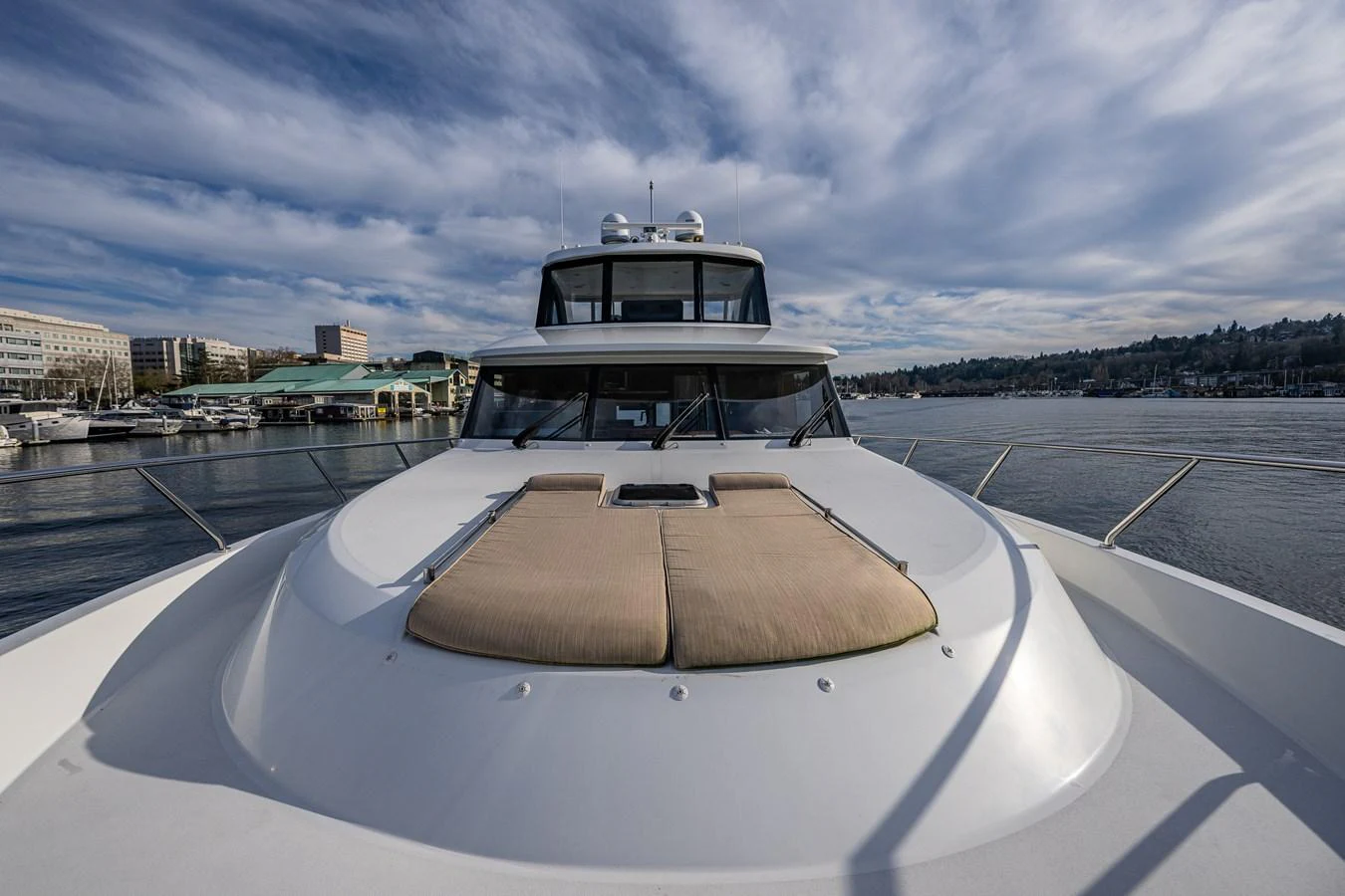 The yacht's foredeck features a spacious sunbathing area with comfortable cushions, set against a scenic marina backdrop. aboard ISLAND BREEZE Yacht for Sale