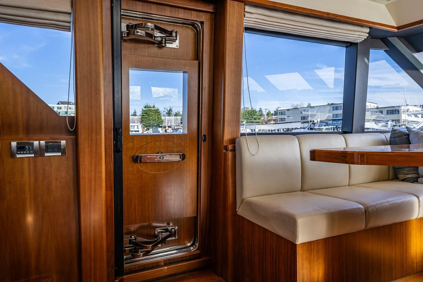 The yacht's interior features a polished wooden door and comfortable seating area with large windows offering a view of the marina. aboard ISLAND BREEZE Yacht for Sale