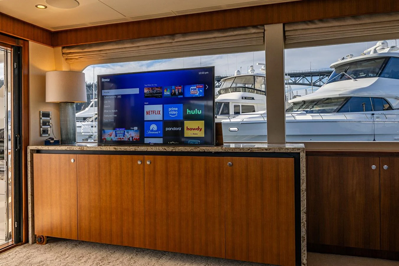The salon features a large flat-screen TV with streaming services, set against a wooden cabinet with a view of the marina outside. aboard ISLAND BREEZE Yacht for Sale