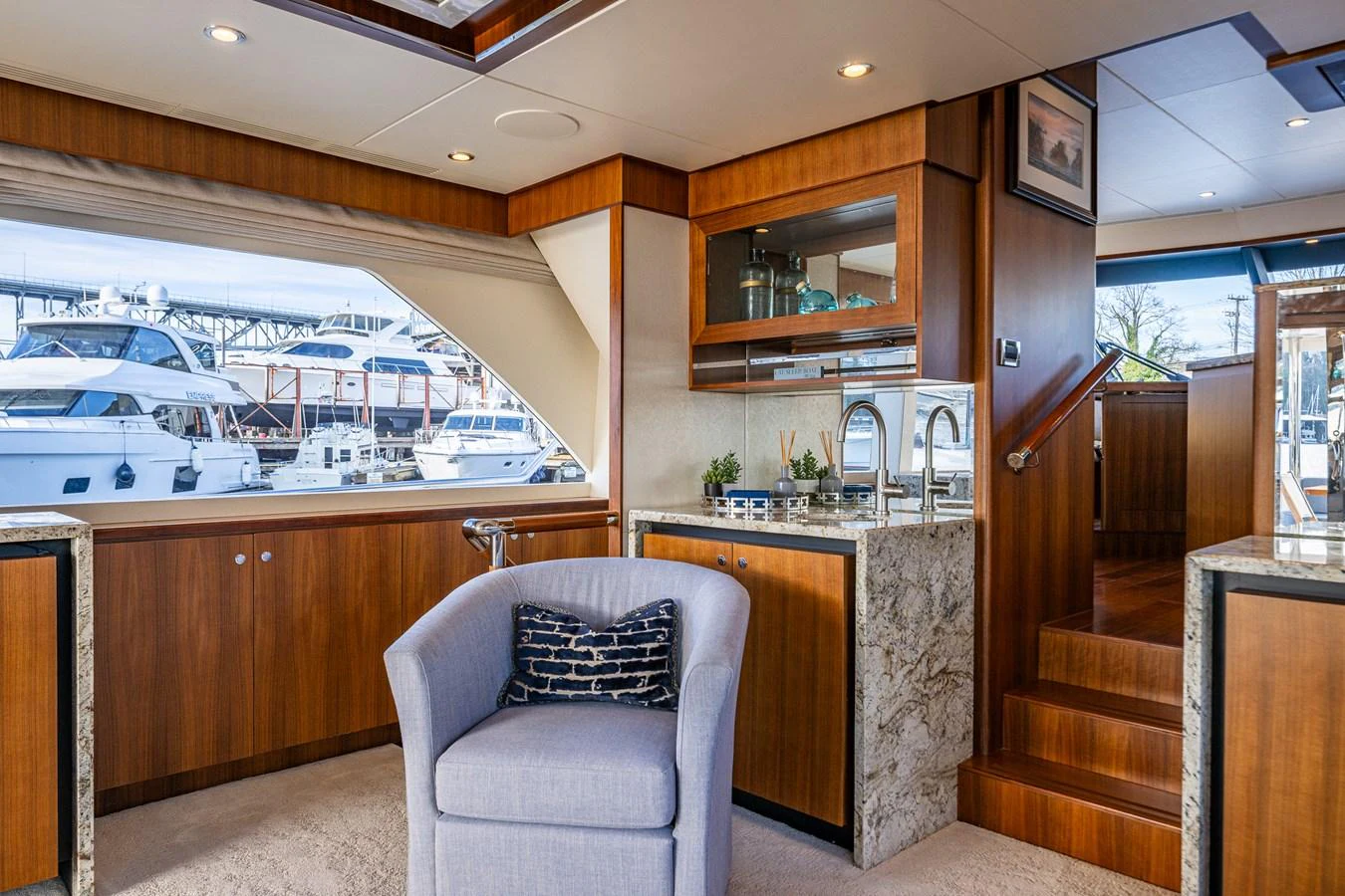The salon features elegant wood finishes, a comfortable armchair, and a well-appointed kitchenette. aboard ISLAND BREEZE Yacht for Sale