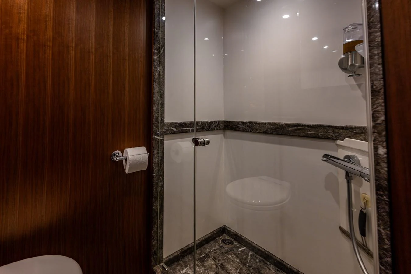A sleek and modern yacht bathroom featuring a glass-enclosed shower and elegant wood paneling. aboard ISLAND BREEZE Yacht for Sale