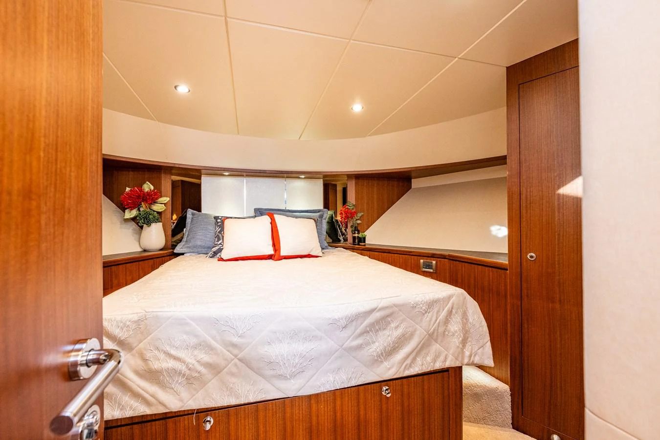 The cozy stateroom features a comfortable bed with elegant bedding and warm wooden accents. aboard ISLAND BREEZE Yacht for Sale