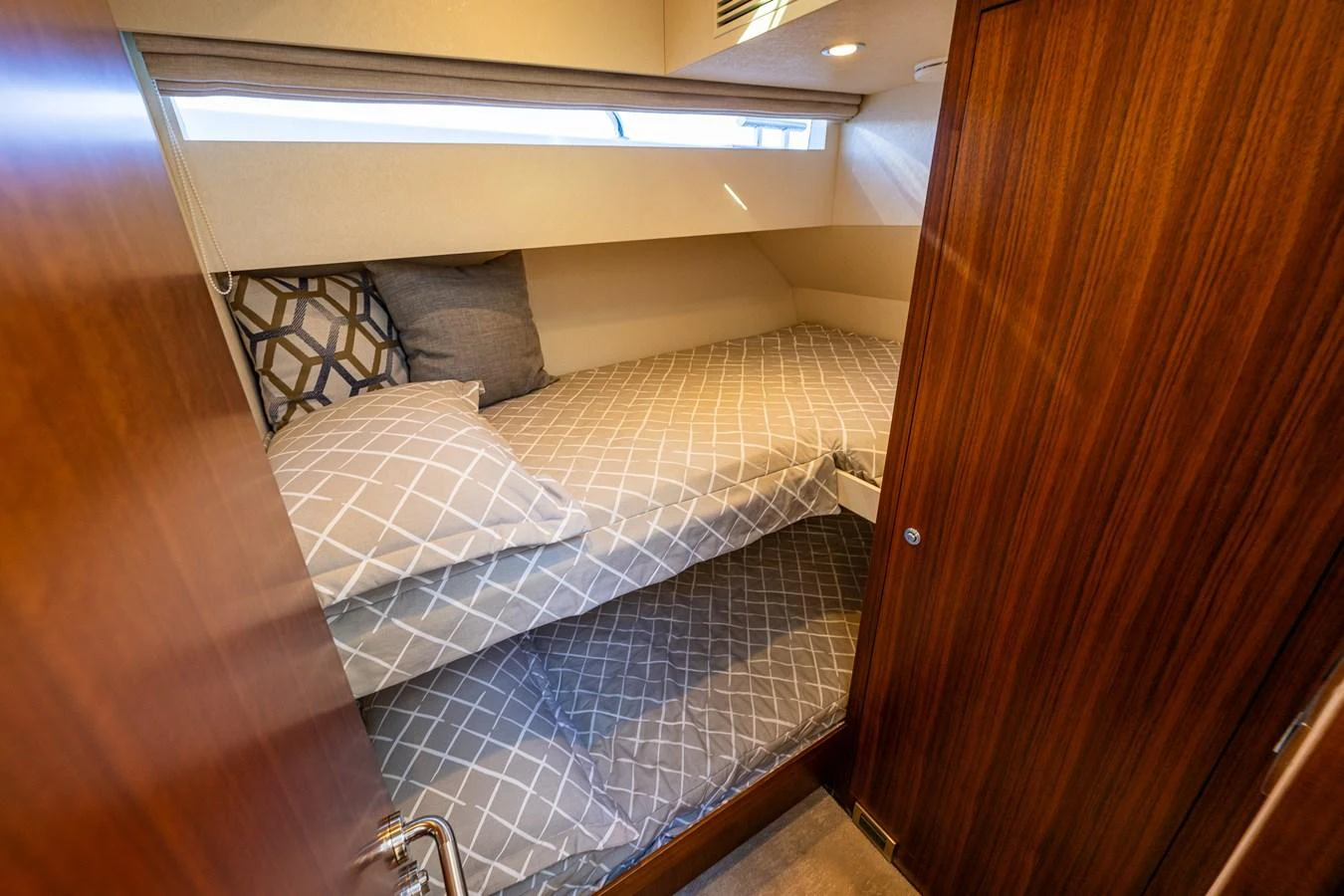 The cozy guest cabin features a comfortable bunk bed with stylish bedding and warm wood finishes. aboard ISLAND BREEZE Yacht for Sale