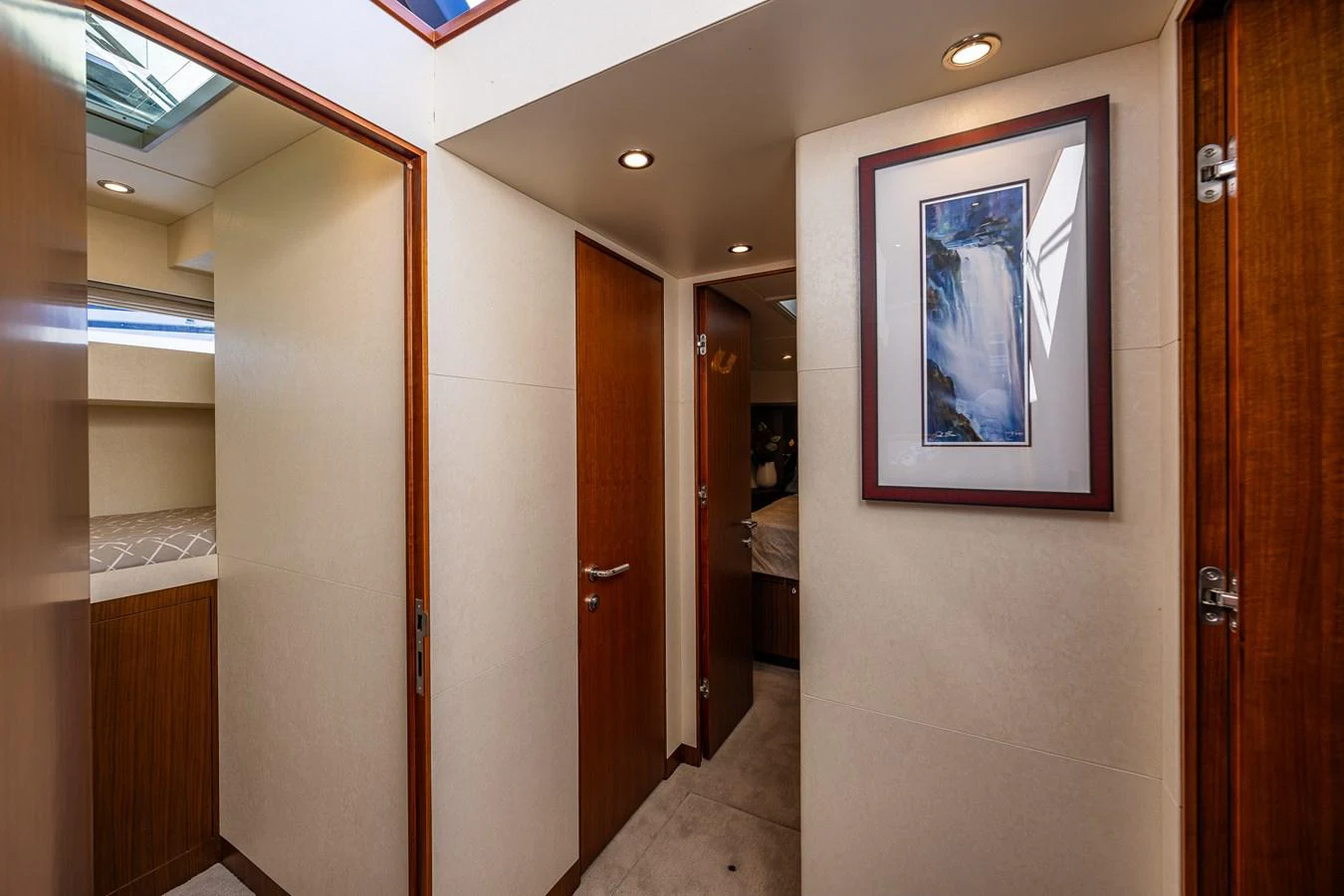 A well-lit hallway with wooden doors and framed artwork, leading to various rooms inside the yacht. aboard ISLAND BREEZE Yacht for Sale