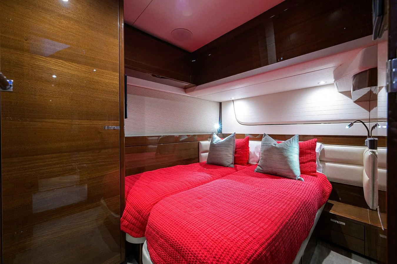 The guest stateroom features twin beds with vibrant red bedding and elegant wooden finishes. aboard MISS AMY Yacht for Sale
