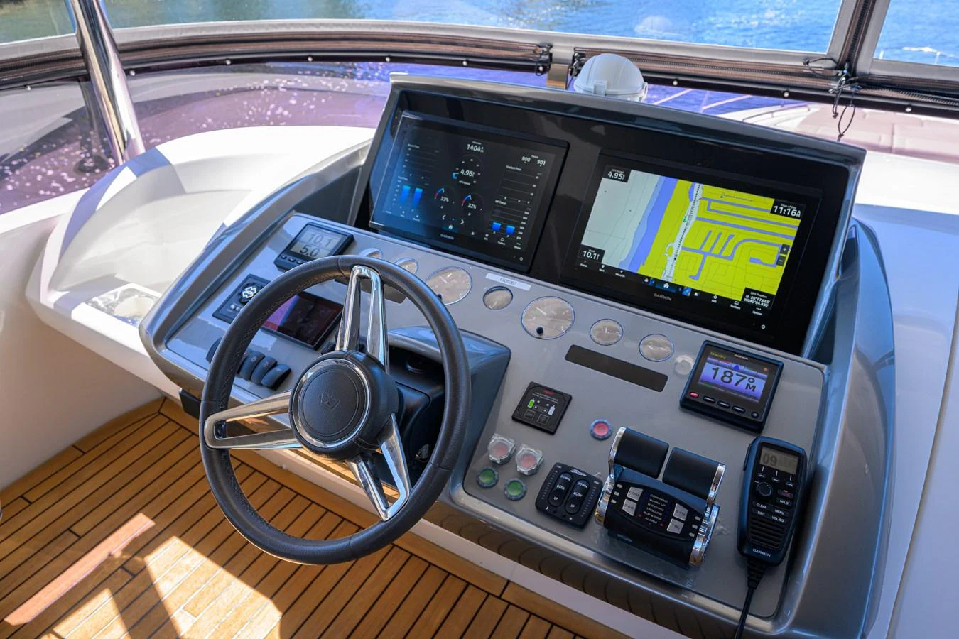 The helm station features advanced navigation equipment and a sleek steering wheel, set against a backdrop of polished wood flooring. aboard MISS AMY Yacht for Sale