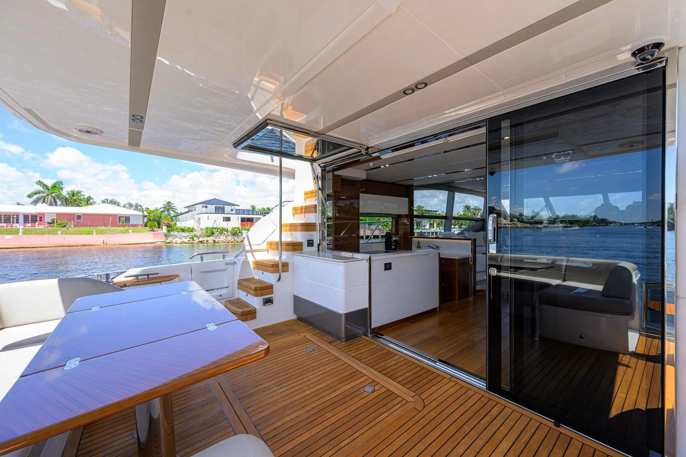 The aft deck features a spacious seating area with a wooden table and easy access to the interior through sliding glass doors. aboard MISS AMY Yacht for Sale
