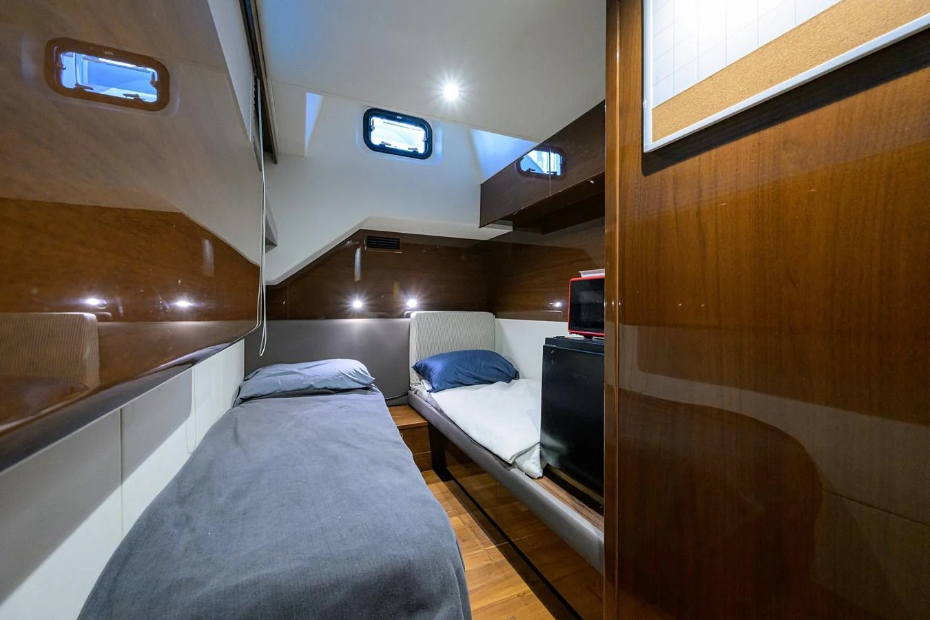 The cozy cabin features twin beds, rich wood paneling, and ample natural light from multiple windows. aboard MISS AMY Yacht for Sale