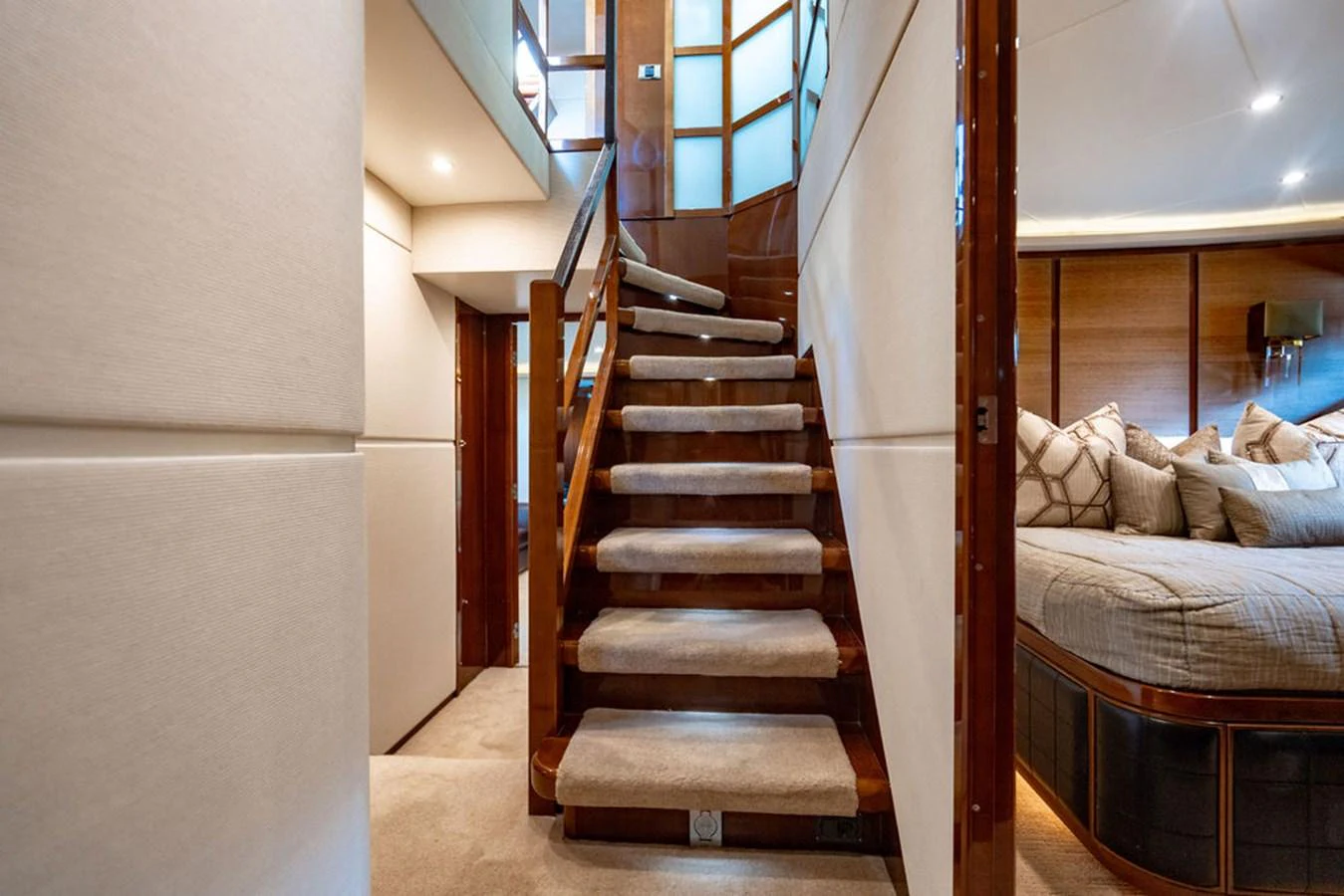 The image showcases a luxurious interior staircase leading to a cozy stateroom. aboard OASIS Yacht for Sale