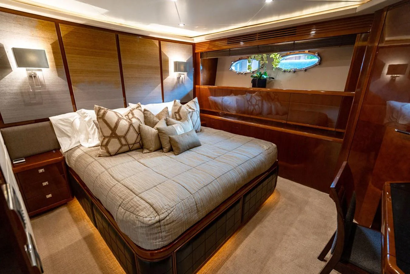 A luxurious stateroom with a large bed, elegant wood paneling, and soft lighting. aboard OASIS Yacht for Sale