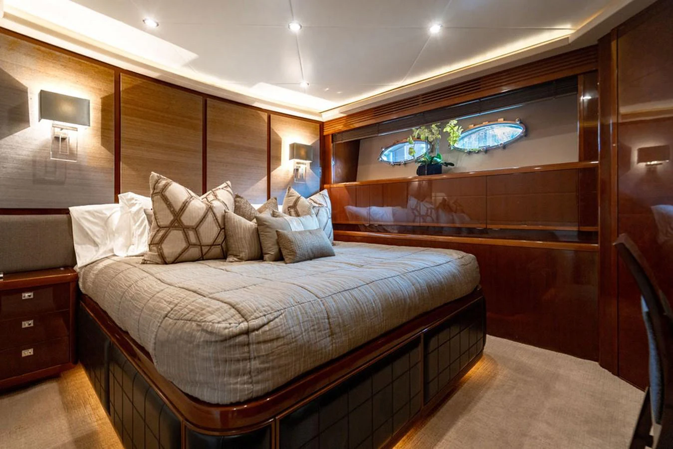 The stateroom features a luxurious bed with plush pillows, warm lighting, and elegant wood finishes. aboard OASIS Yacht for Sale