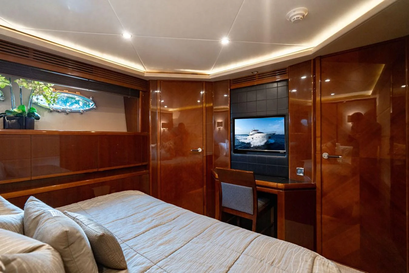 The stateroom features luxurious wood paneling, a comfortable bed, and a flat-screen TV. aboard OASIS Yacht for Sale