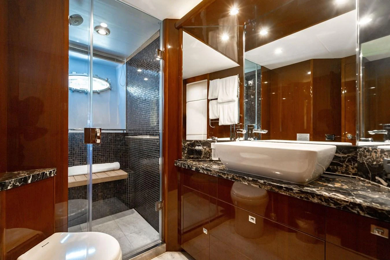 The yacht's bathroom features a sleek design with a glass-enclosed shower and elegant fixtures. aboard OASIS Yacht for Sale