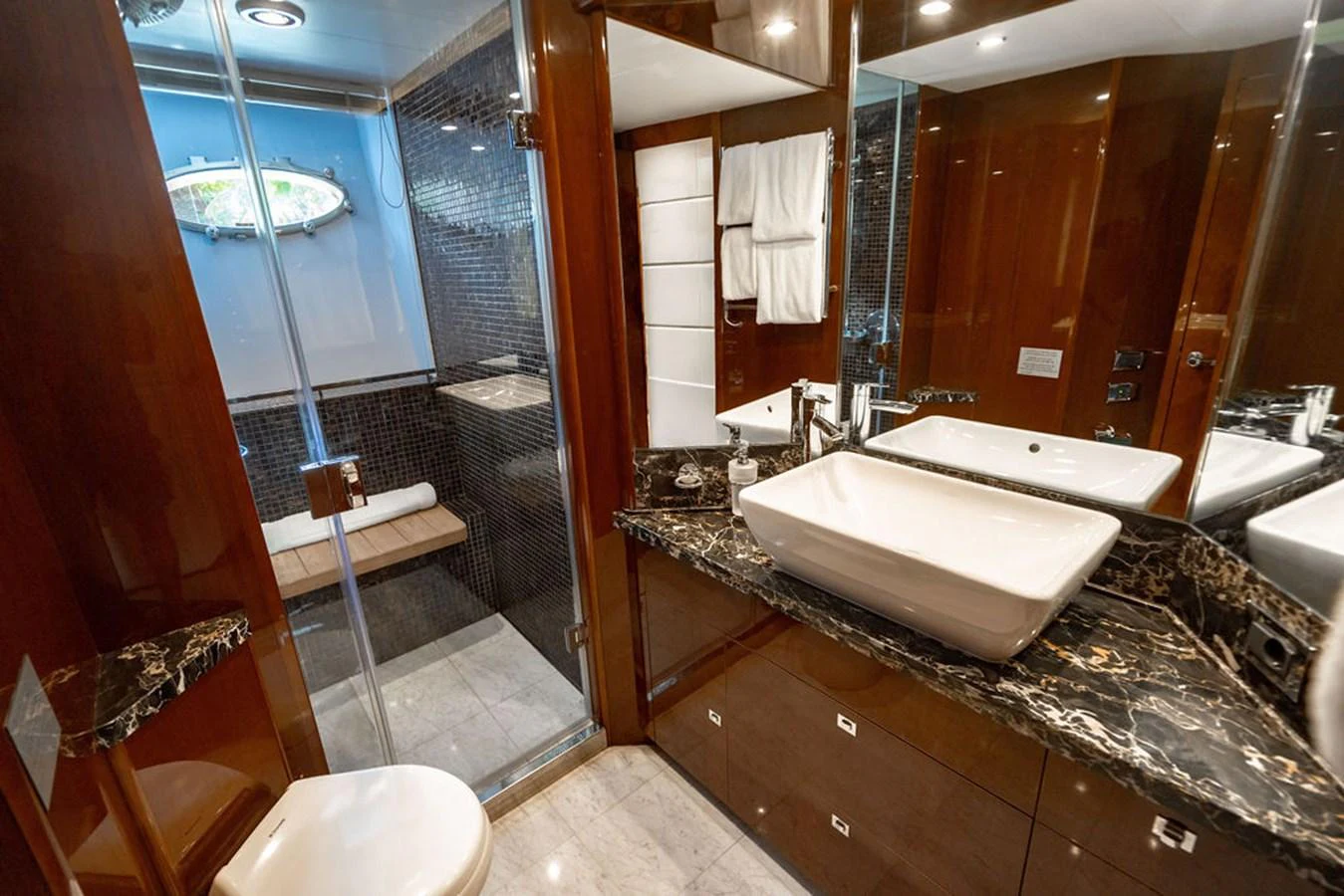 The yacht's bathroom features luxurious marble countertops and a spacious glass-enclosed shower. aboard OASIS Yacht for Sale