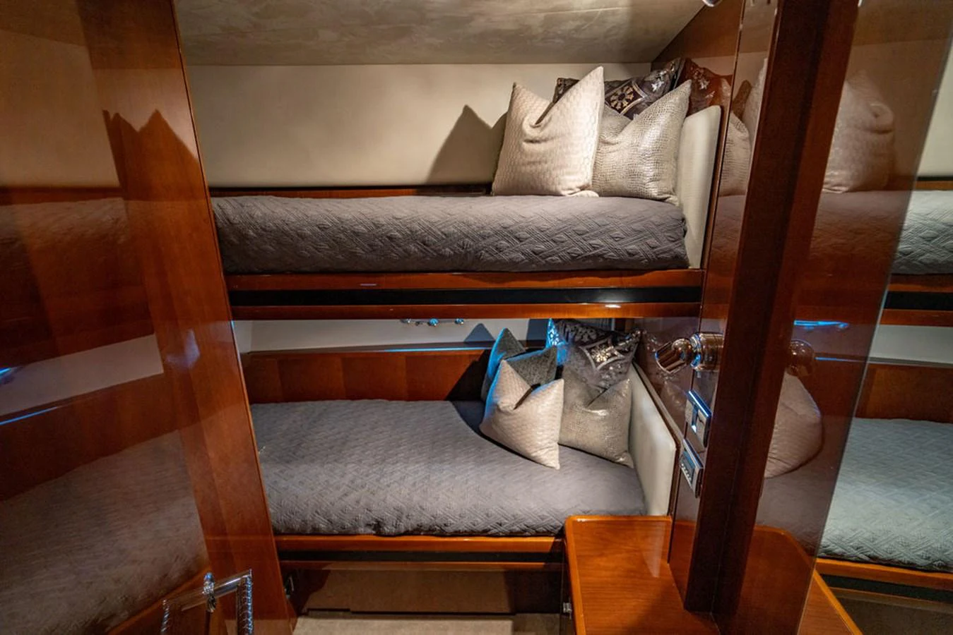 The guest cabin features cozy bunk beds with plush pillows and elegant wood finishes. aboard OASIS Yacht for Sale