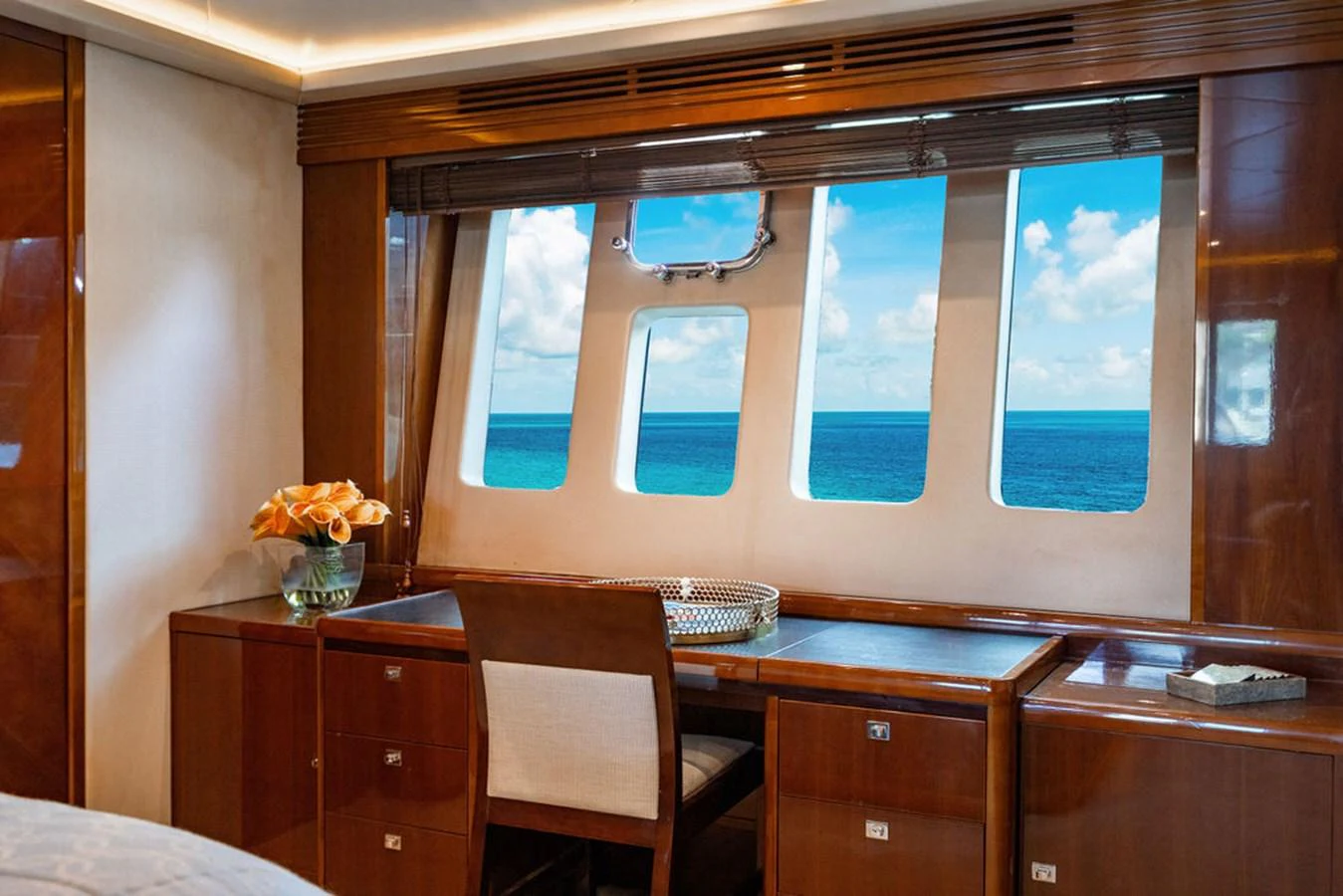 The stateroom features a desk with a stunning ocean view through large windows. aboard OASIS Yacht for Sale