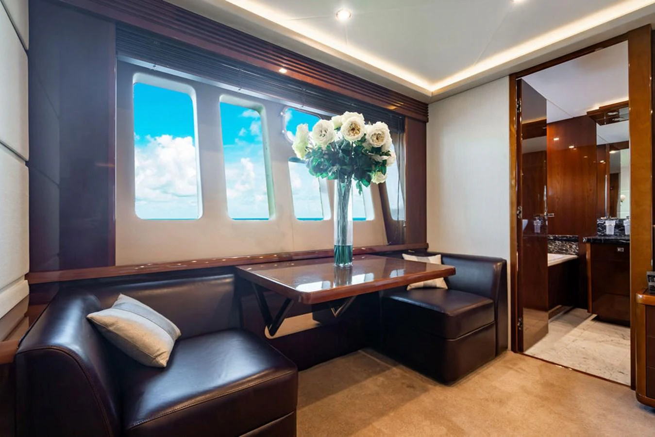 The yacht's dining area features a cozy seating arrangement with a table and large windows offering a view of the sea. aboard OASIS Yacht for Sale
