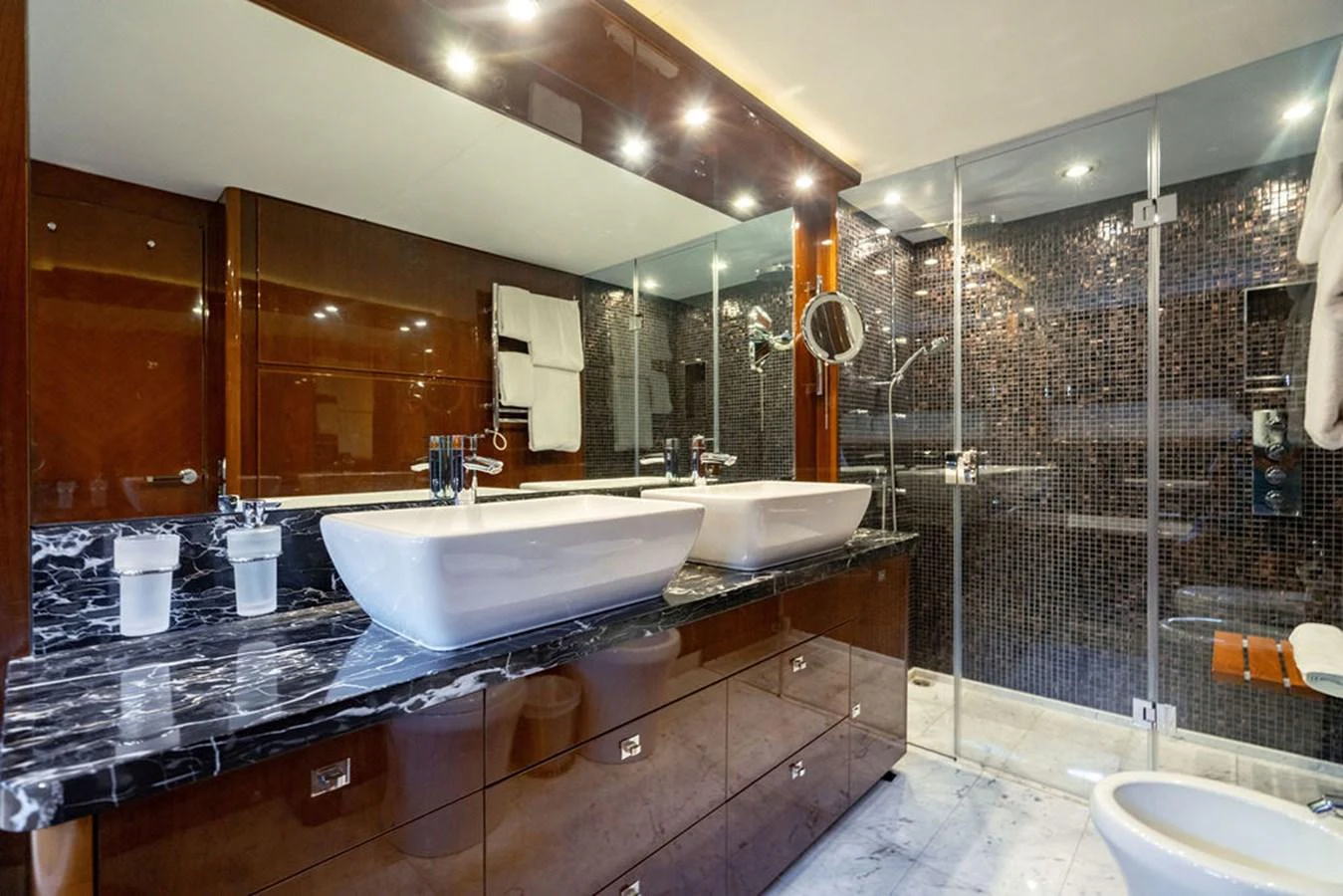 The yacht's bathroom features a luxurious design with double sinks, a marble countertop, and a spacious glass-enclosed shower. aboard OASIS Yacht for Sale