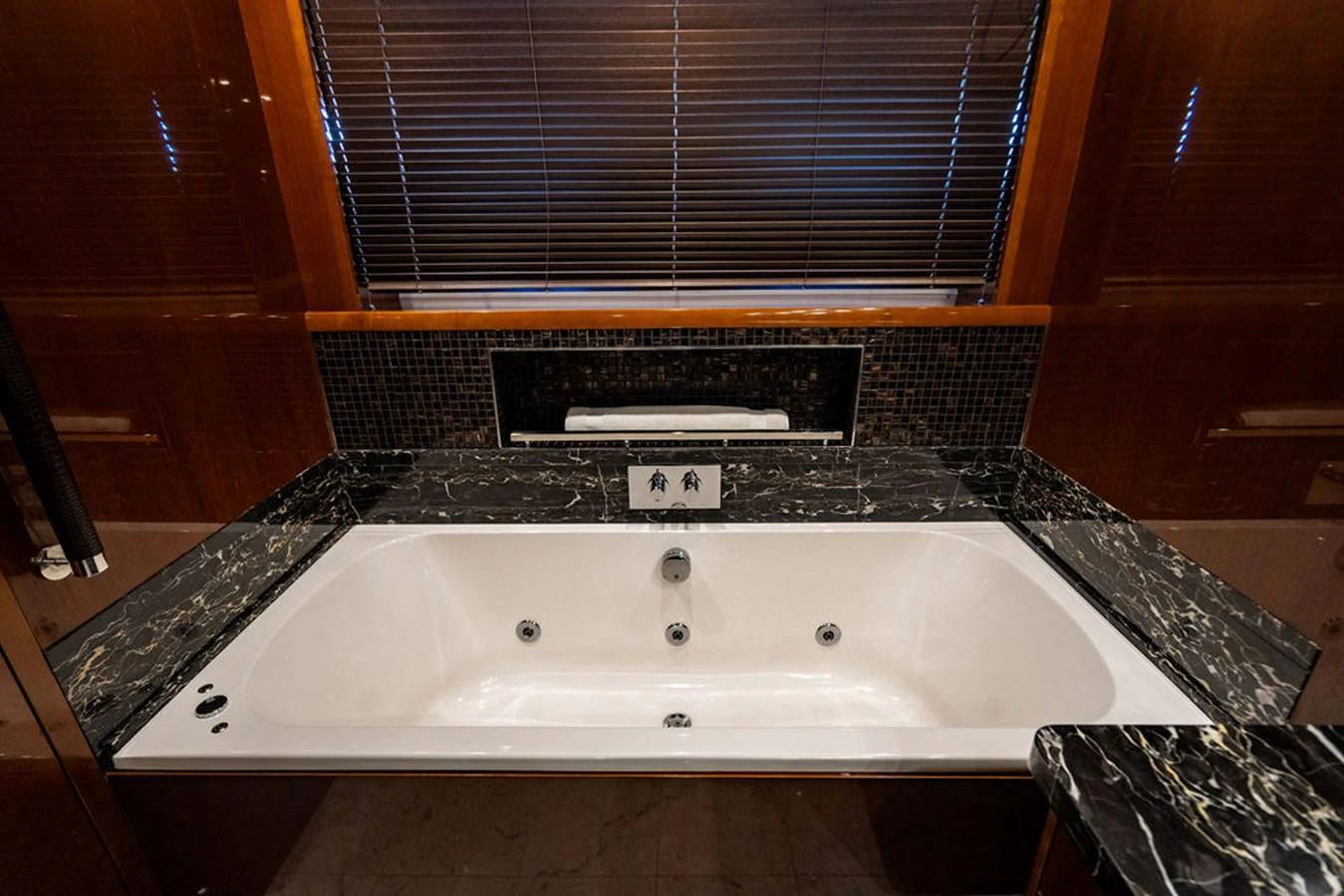 The yacht's bathroom features a luxurious marble jacuzzi tub with elegant dark wood accents. aboard OASIS Yacht for Sale