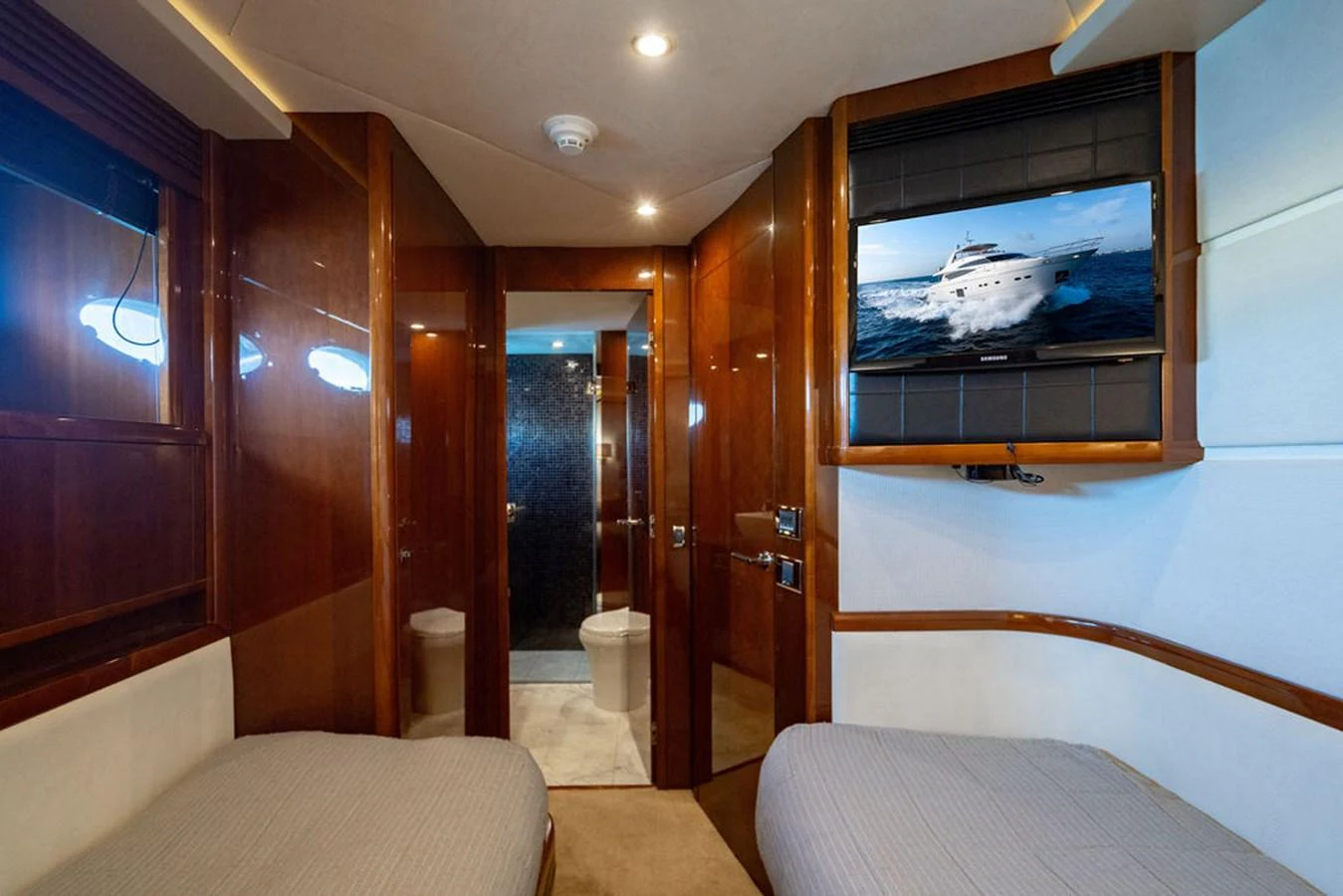 A cozy guest cabin featuring twin beds and a flat-screen TV. aboard OASIS Yacht for Sale