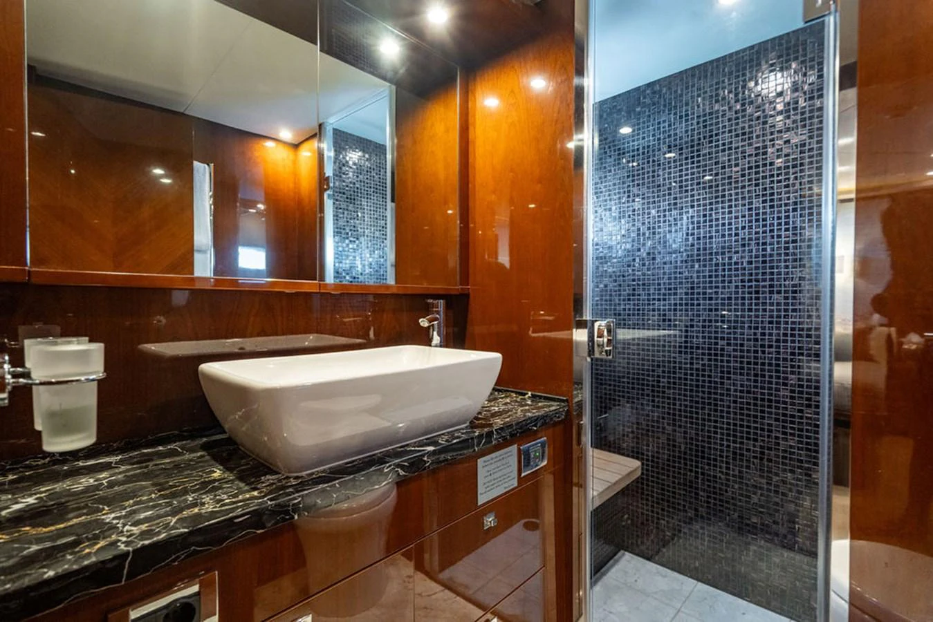 The yacht's bathroom features a sleek design with a modern sink and a stylish tiled shower area. aboard OASIS Yacht for Sale