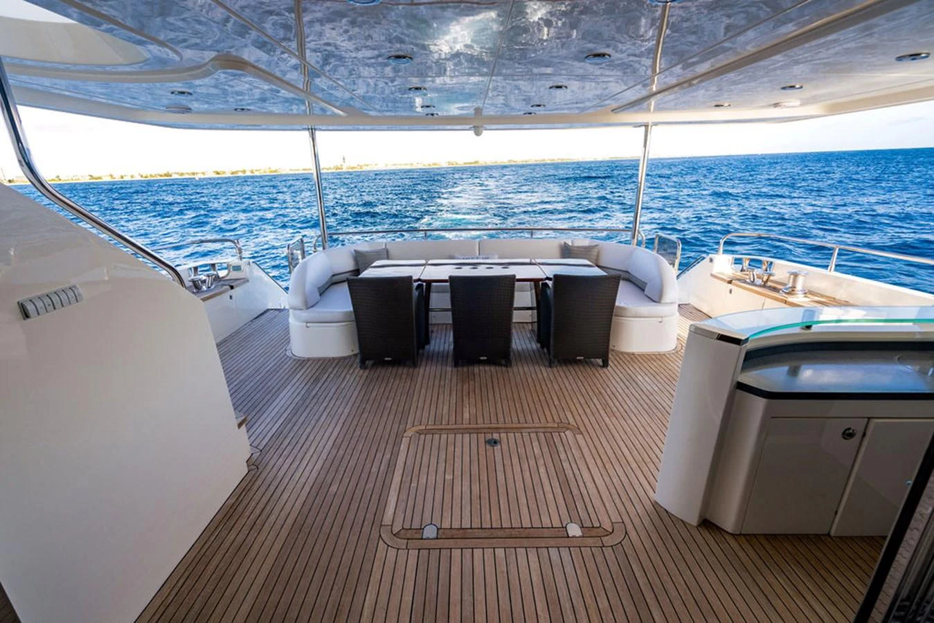 The aft deck features a spacious seating area with a dining table, offering stunning views of the open sea. aboard OASIS Yacht for Sale