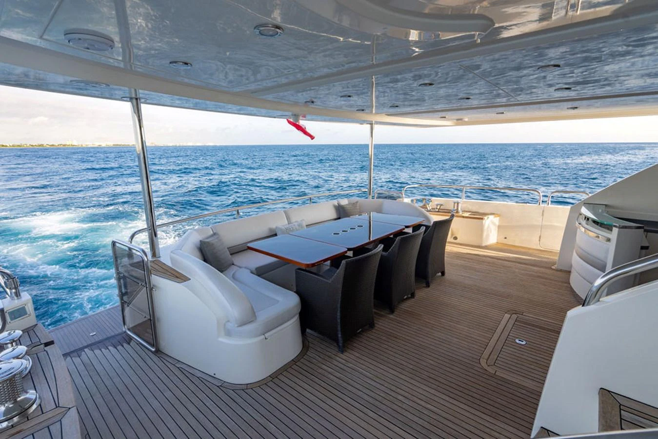The aft deck features a spacious seating area with a large dining table, perfect for alfresco dining with stunning ocean views. aboard OASIS Yacht for Sale