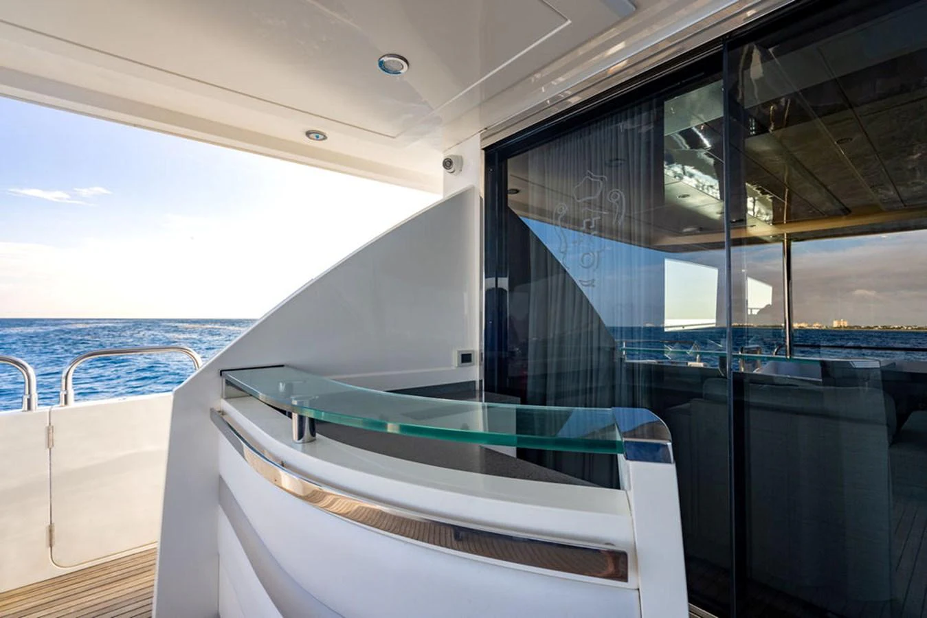 The aft deck offers a sleek and modern space with a glass railing and a view of the ocean. aboard OASIS Yacht for Sale