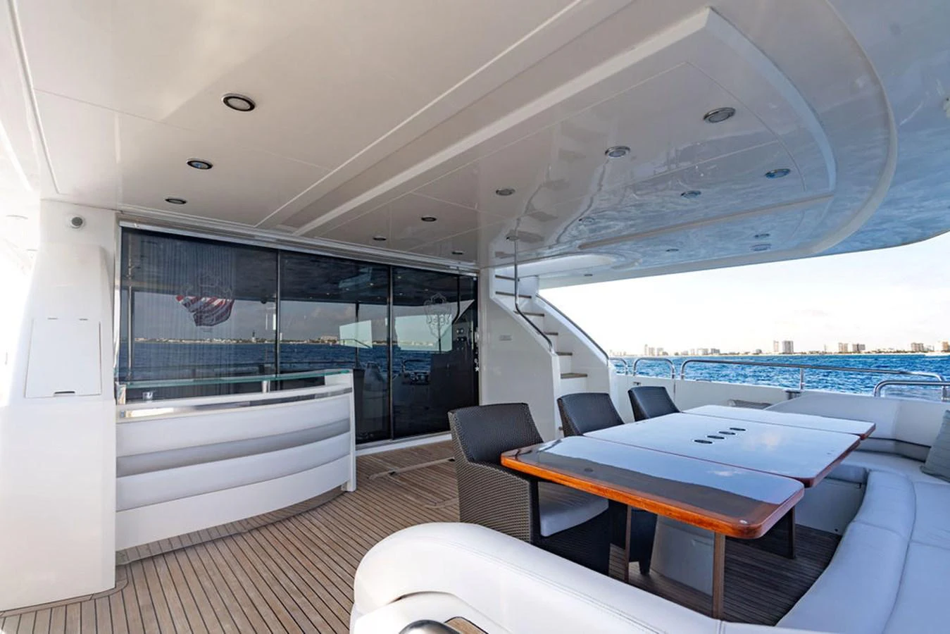 The aft deck features a spacious dining area with a sleek table and comfortable seating, perfect for al fresco dining. aboard OASIS Yacht for Sale