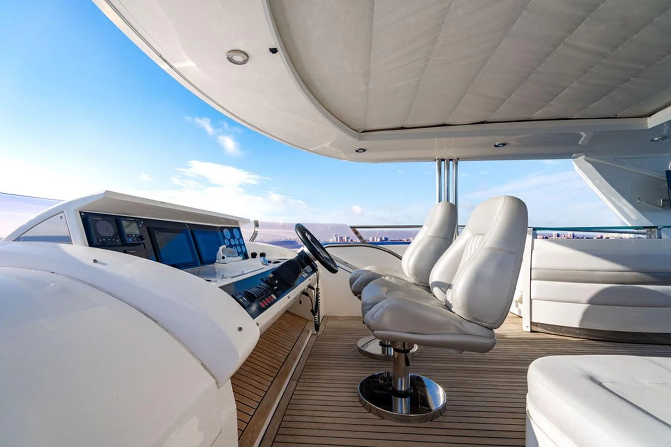 The yacht's helm features sleek, modern seating and advanced navigation equipment under a protective canopy. aboard OASIS Yacht for Sale