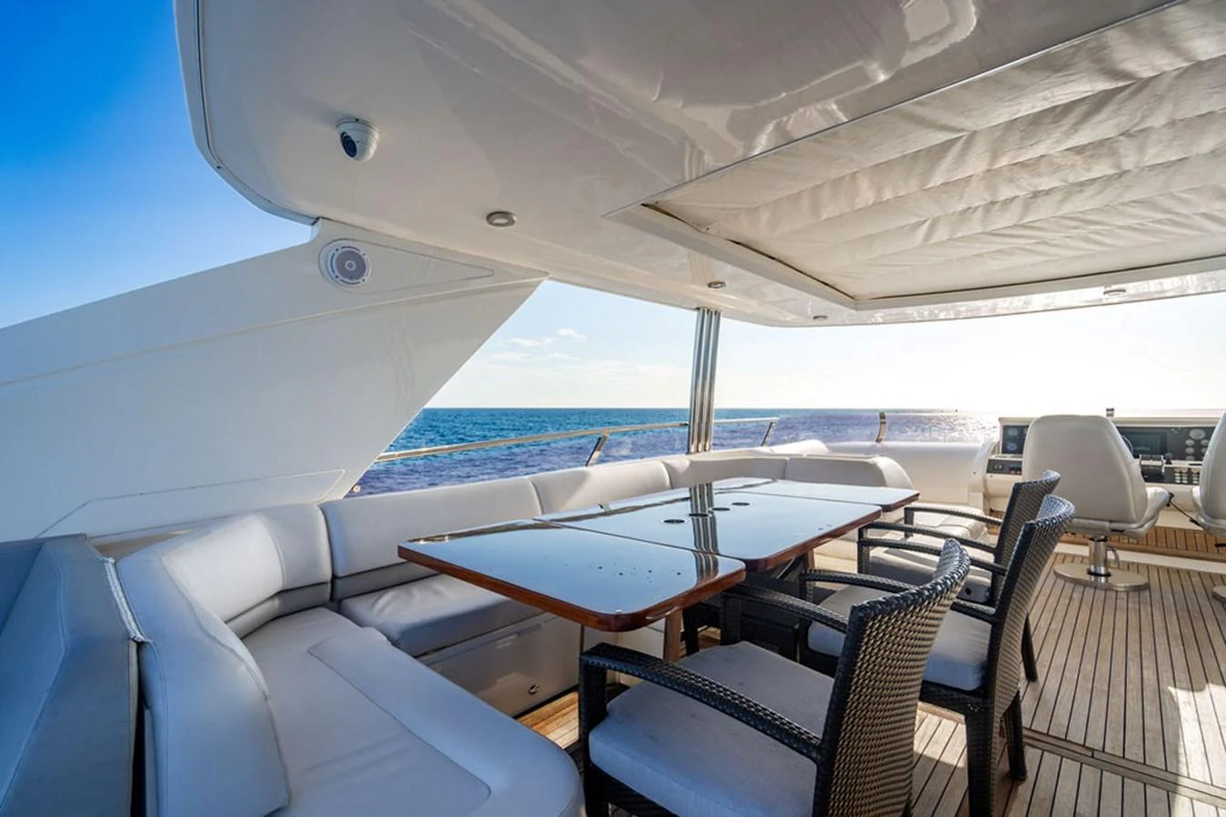 The aft deck features a spacious seating area with a polished wooden table, perfect for alfresco dining with an ocean view. aboard OASIS Yacht for Sale