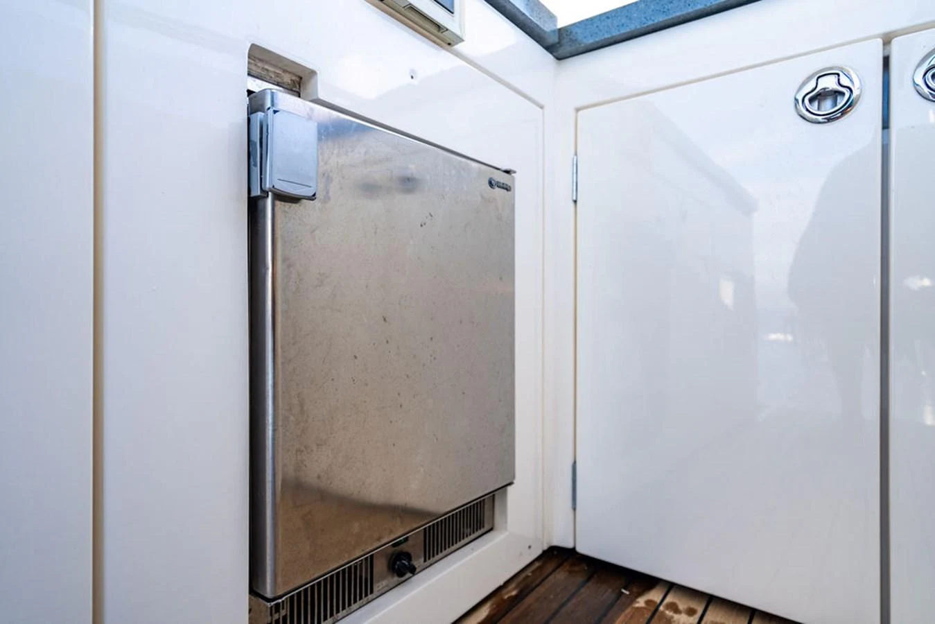 A close-up view of a stainless steel appliance door on a yacht, set against a clean white background with wooden flooring. aboard OASIS Yacht for Sale