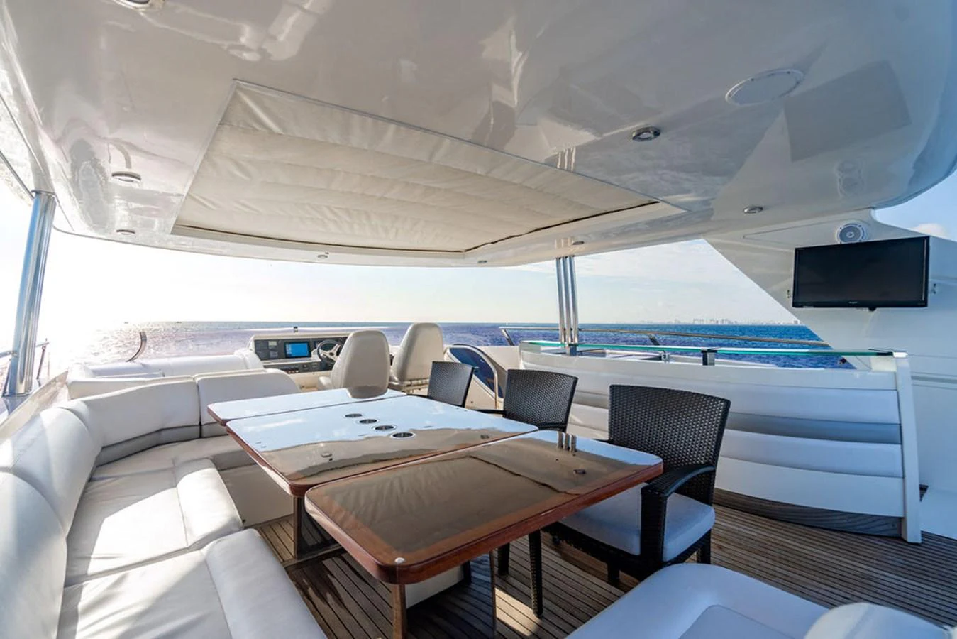 The flybridge features a spacious seating area with a table and a view of the sea. aboard OASIS Yacht for Sale